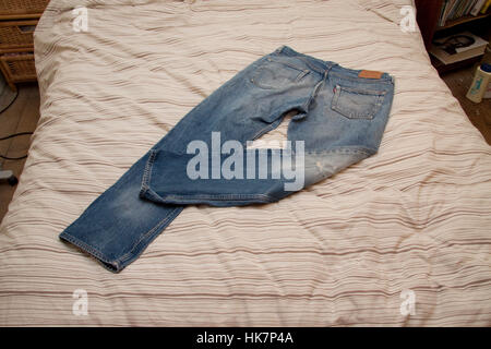 Indossare jeans blu su un letto quilt Foto Stock