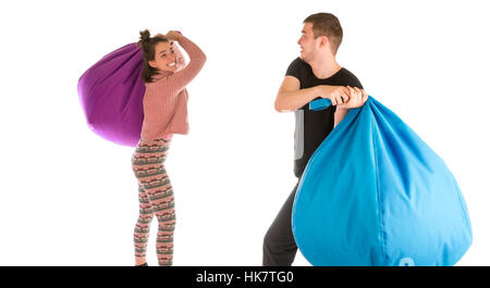 Funny giovane maschio e femmina combattimenti con sedie beanbag isolati su sfondo bianco Foto Stock