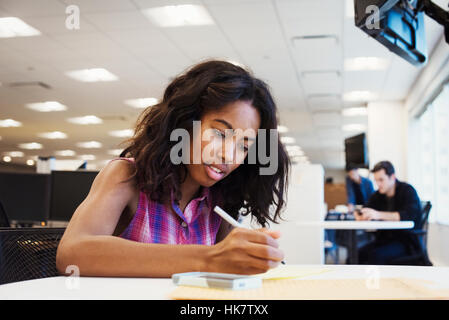 Una donna seduta su un tavolo o in un ufficio della scrittura. Foto Stock