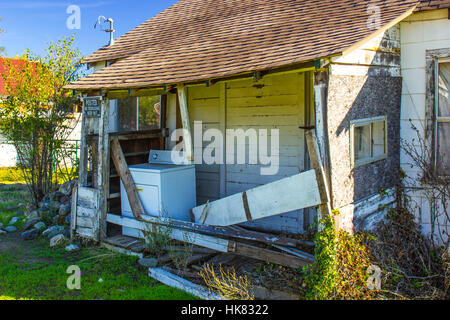 Abbandonato Casa in rovina con macchina di lavaggio sul portico anteriore Foto Stock