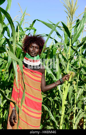 KENYA Turkana, Lodwar, villaggio Turkana Kaitese, Turkana donna con parrucca nella parte anteriore del campo di mais Foto Stock