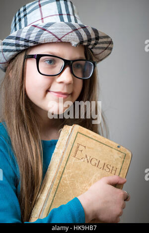 Grave la ragazza di occhiali e cappello a scacchi con libro inglese in mani Foto Stock