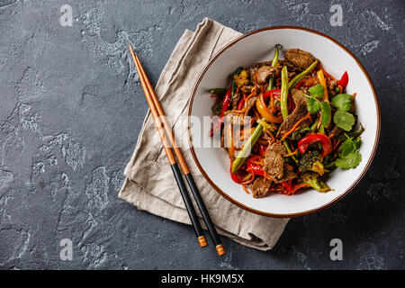 Rosolare la carne bovina con verdure nella ciotola in pietra scura sullo sfondo Foto Stock