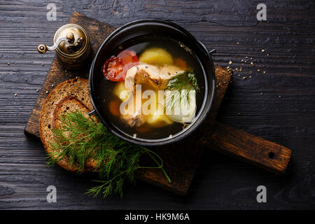 Zuppa di pesce con salmone, le patate e le carote in ferro nero sulla pentola bruciato nero lo sfondo di legno Foto Stock