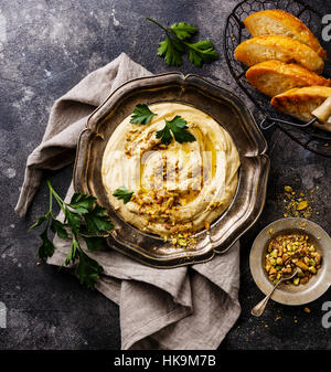 In casa hummus con pistacchi e crostini di pane nella piastra di metallo nero su sfondo di pietra da vicino Foto Stock