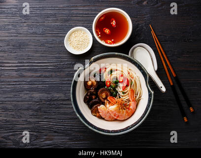 Spaghetti ramen con gamberi e funghi shiitake con brodo scuro su sfondo di legno Foto Stock