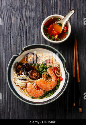 Spaghetti ramen con gamberi e funghi shiitake con brodo scuro su sfondo di legno Foto Stock