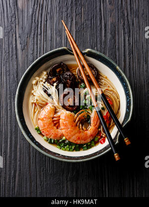 Spaghetti ramen con gamberi e funghi shiitake in brodo scuro su sfondo di legno Foto Stock