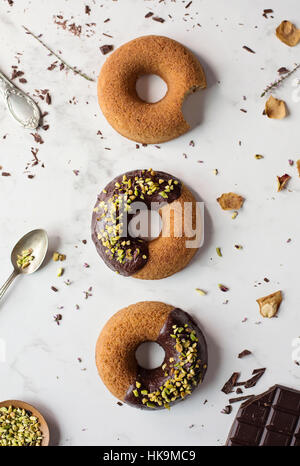 Le ciambelle con cioccolato e pistacchi sulla tavola di marmo Foto Stock