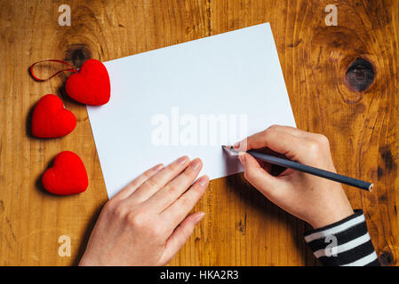 Donna scrivere lettera d'amore o una romantica poesia per il giorno di San Valentino, vista dall'alto Foto Stock