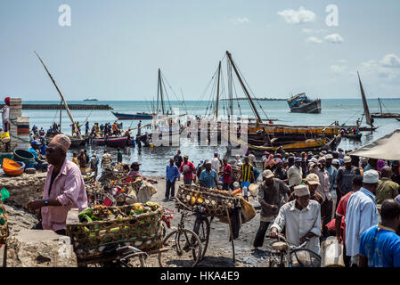 Persone affare per il prezzo migliore per acquistare il pesce in un mercato locale del pesce al vecchio porto Dhow, città di Zanzibar, Zanzibar, Tanzania. I pescatori portano il pesce al mercato per gli operatori i quali acquistano il pesce per rivenderlo nel mercato di Stone Town. Foto Stock