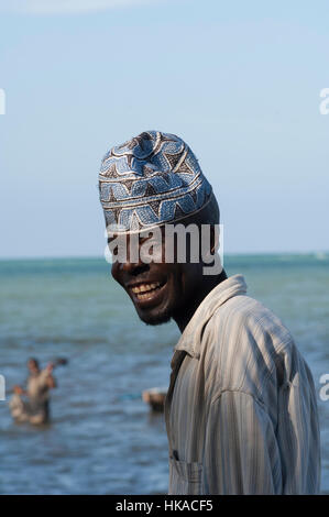 I pescatori in piedi spingendo la loro barca con poli, Palm Tree spiaggia orlata di sfondo, Kilwa, Tanzania Foto Stock