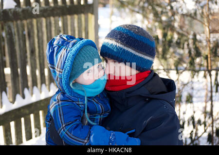 Padre e figlio giocare nella neve insieme indossando Cappello invernale giacca guanti e sciarpa Foto Stock
