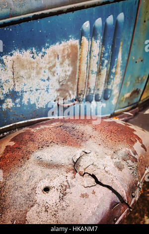 Tonalità di colore da vicino la foto di un vecchio arrugginito incrinato parafango auto, il fuoco selettivo, grunge background. Foto Stock