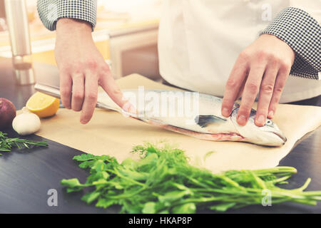 Lo chef prepara il pesce salmone per la cottura in cucina Foto Stock