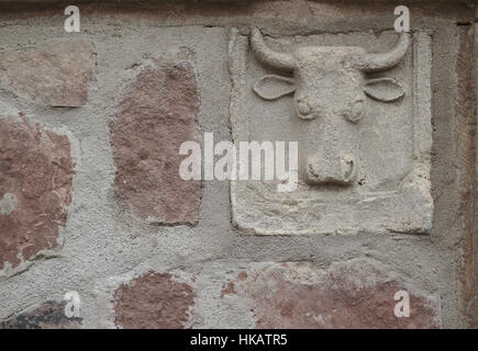 Testa di toro scolpita nella pietra di un muro di casa Foto Stock