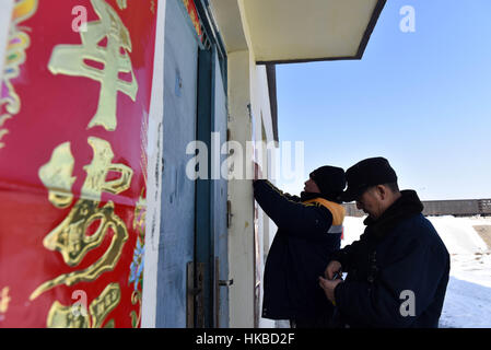 Karamay. 27 gennaio, 2017. Membro dello staff Hao Chunjie (R) e Wei Fucheng pasta Festival di Primavera baciata su una porta in corrispondenza di una remota logistica ferroviaria stazione vicino il Manas Lago, a nord-ovest della Cina di Xinjiang Uygur Regione autonoma, Gennaio 27, 2017, alla vigilia del nuovo anno lunare cinese. Credito: Hu Huhu/Xinhua/Alamy Live News Foto Stock