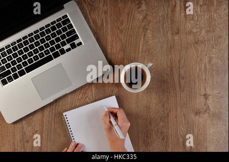 Persona scrivendo in notebook infront di laptop Foto Stock