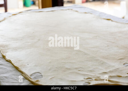 Fillo fatti in casa o la pasta dello strudel su una casa tovaglia, pronto per lo strudel di mele, baklava, burek, torta o altri tipi di dolci tradizionali. Foto Stock