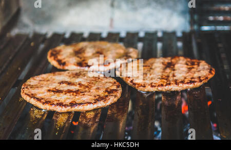 Grigliare gli hamburger sul barbecue grill barbecue a carbone caldo. In casa gli hamburger vengono arrostite su ECO grill bar per mangiare sano e cottura. Foto Stock