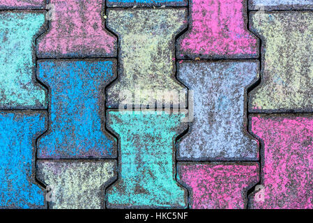 Colorate di ciottoli di cemento grigio a forma di H marciapiede in lastre o pietre. Bambini colorato pavimento con gessi colorati. Artistico e creativo per childr Foto Stock