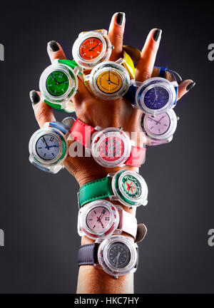 Una mano insegna a diversi orologi simili su diversi colori Foto Stock