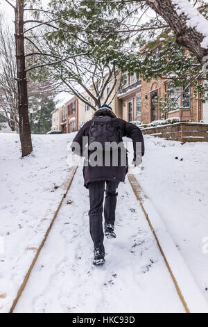 Uomo che corre sul marciapiede coperto in inverno la neve sul pendio collinare nelle vicinanze Foto Stock