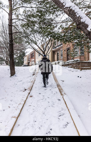 Uomo che corre sul marciapiede coperto in inverno la neve sul pendio collinare nelle vicinanze Foto Stock