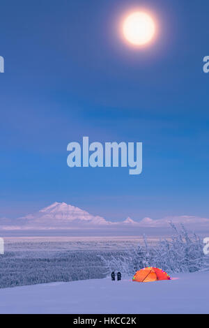 La luna piena al di sopra di un Monte Nevoso tamburo e il rame River Valley con una tenda e le racchette da neve in primo piano, centromeridionale Alaska, STATI UNITI D'AMERICA, inverno Foto Stock