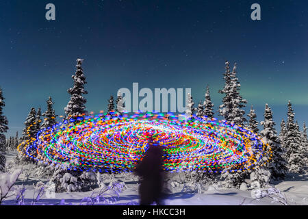 L'Aurora Borealis Danze sopra la parte superiore di Una pittura vibrante della luce a spirale, la figura blurry di Un uomo nel mezzo della pittura della luce, Moonlig... Foto Stock