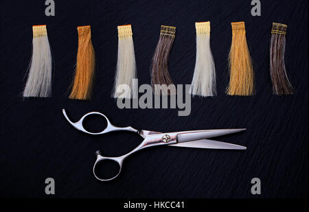 Parrucchiere accessori per la colorazione dei capelli e le estensioni di colori su uno sfondo nero. Forbici e campioni di capelli Foto Stock