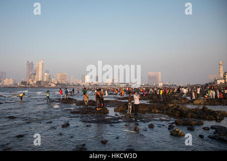 Le persone che giocano sulle rocce che circondano Haji Ali Dargah, una Moschea Islamica e la tomba di Mumbai (Bombay), India. Foto Stock