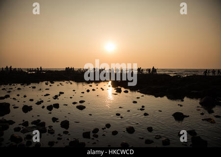 Persone profilarsi a bassa marea sulle rocce che surroundHaji Ali Dargah, una Moschea Islamica e la tomba di Mumbai (Bombay), India. Foto Stock