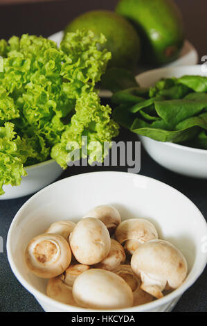 Di funghi freschi di piastra con verdi su uno sfondo Foto Stock