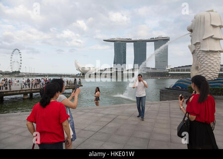 SINGAPORE, Singapore - 22 febbraio 2016: turisti prendere le foto di fronte alla Marina Sands edificio e la statua Merlion nella baia di Singapore Foto Stock