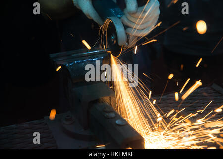 Lavoratore il taglio con la fresa e metallo di saldatura con molti sharp scintille in fabbrica Foto Stock