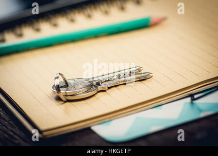 Coppia di chiavi sul blocco note giallo vicino a matita verde. Il concetto di memoria Foto Stock