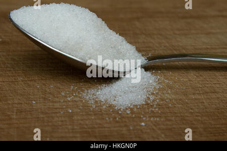 Cucchiaio di zucchero su uno sfondo di legno Foto Stock