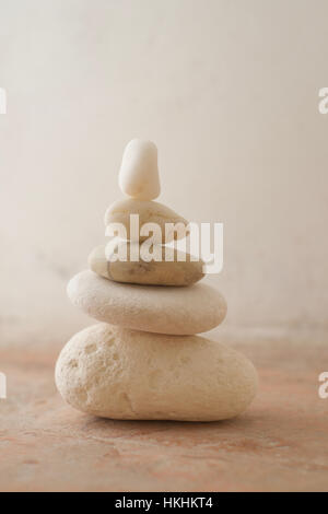 Una pila di ciottoli con toni chiari contro un sfondo rustico Foto Stock