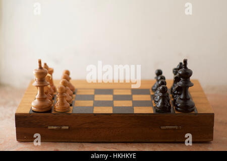 Una metà scacchiera di bianco e nero con pezzi di scacchi disposte affacciate a vicenda Foto Stock