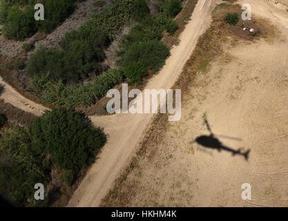10/13/11 - L'ombra del Texas Dipartimento della Pubblica Sicurezza elicottero si muove attraverso i campi di coltivazione e spazzola paese mentre pattugliano il Texas/Me Foto Stock