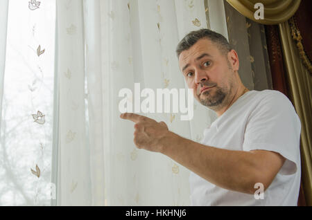 Giovane uomo in piedi su una finestra puntando a destra Foto Stock