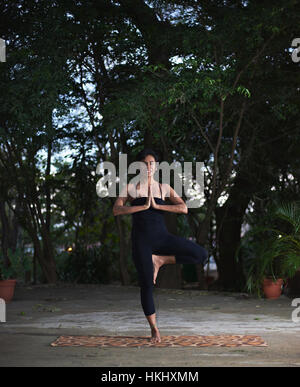 Donna fare yoga pone nel giardino della sera Foto Stock