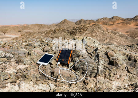 La ricarica dello smartphone con energia solare banca con doppia porta USB con Rocky Mountain come sfondo Foto Stock