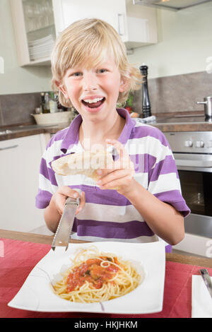 Ritratto di un ragazzo felice grattugiare il formaggio su spaghetti,Baviera,Germania Foto Stock