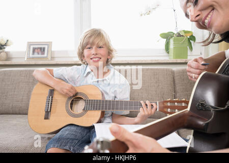 Donna con suo figlio a suonare la chitarra in soggiorno, Baviera, Germania Foto Stock