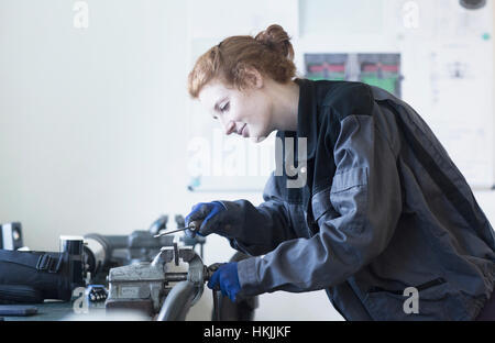 Femmina giovane ingegnere morsa utilizzando lo strumento di presa in un impianto industriale di Freiburg im Breisgau, Baden-Württemberg, Germania Foto Stock