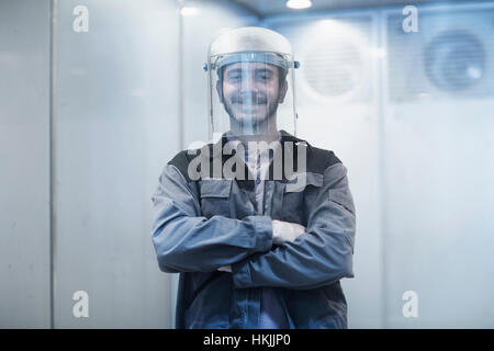 Ritratto di un giovane ingegnere di sesso maschile che indossa il casco nella tecnologia spaziale e sorridente, Freiburg im Breisgau, Baden-Württemberg, Germania Foto Stock