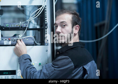 Giovane ingegnere maschio spina di collegamento nel router nella tecnologia spaziale, Freiburg im Breisgau, Baden-Württemberg, Germania Foto Stock