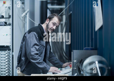 Giovane ingegnere maschio l'aggiornamento di Pannello di controllo nella sala di controllo, Freiburg im Breisgau, Baden-Württemberg, Germania Foto Stock